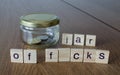 Swear jar `Jar of f*cks`on the wooden table background. Royalty Free Stock Photo