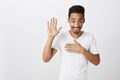 Swear to say truth. Studio shot of sincere happy african-american male with afro haircut, raising palm and holding hand Royalty Free Stock Photo