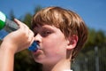 Sweating Boy is drinking water out of a bottle