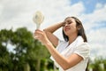 A sweaty Asian woman using a portable handy fan, feeling hot and tired, rests after a long run