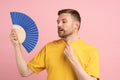 Sweaty exhausted man using paper fan suffer from heat. Overheating, stuffiness, hot weather concept Royalty Free Stock Photo