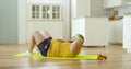 Sweaty fat man in wet yellow sportswear doing abs crunch exercise at home.