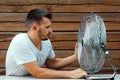 Sweaty man in front of a cooling ventilator, refreshing in the concept of hot summer. The concept of salvation from the heat, hot