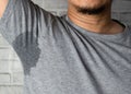 Sweaty man with stain wet armpit on t-shirt against gray Royalty Free Stock Photo