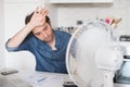 Sweaty man trying to refresh from heat with a fan Royalty Free Stock Photo