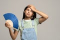 Sweaty teenage girl touching forehead using paper fan suffer from heat cooling in hot summer weather Royalty Free Stock Photo