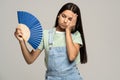 Sweaty teenage girl touching forehead using paper fan suffer from heat cooling in hot summer weather Royalty Free Stock Photo