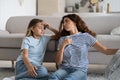 Sweaty tired woman sits on floor next to sofa and fan looking back at teenage girl after summer walk Royalty Free Stock Photo