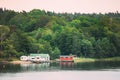 Sweden. Beautiful Red Swedish Wooden Log Cabin House On Rocky Island Coast In Summer. Lake Or River And Forest Landscape Royalty Free Stock Photo