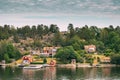 Sweden. Beautiful Red Swedish Wooden Log Cabin House On Rocky Island Coast In Summer Sunny Evening. Lake Or River Royalty Free Stock Photo