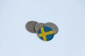 Sweden flag on the coin with heap of Swedish Krona money on white background. Concept of finance