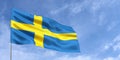 Sweden flag on flagpole on blue sky background. Swedish flag waving in the wind on a background of sky with clouds. Place for text Royalty Free Stock Photo