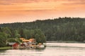 Sweden. Many Beautiful Red Swedish Wooden Log Cabins Houses On Rocky Island Coast. Lake Or River Landscape Royalty Free Stock Photo