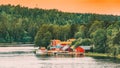 Sweden. Many Beautiful Red Swedish Wooden Log Cabins Houses On Rocky Island Coast In Summer Evening. Lake Or River Royalty Free Stock Photo
