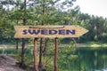 Sweden wooden arrow road sign against lake and pine trees background. Travel to Sweden concept