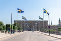 Swedish flags on metal poles along a street highway. Tourists people walk on a sunny day. Royalty Free Stock Photo