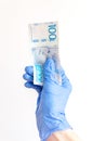 100 Swedish krona banknote in hand in surgical gloves.