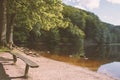 A lake with an old wooden bench in the middle of a rich forest. Royalty Free Stock Photo