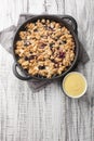 Swedish pie Smulpaj baked with apples and blueberries close-up in a pan. Vertical top view