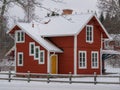 Swedish red two storeywooden family houses behind a snow covered tree alongside the snow surfaced road in the residential area Royalty Free Stock Photo