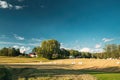 Swedish Rural Landscape Field Meadow With Dry Hay Bales During Harvest In Sunny Evening. Farmland With Red Farm Barn