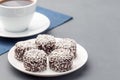 Swedish sweets chocolate balls or chokladbollar, made from oats, cocoa, butter and coconut, on white plate, served with coffee,