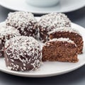 Swedish sweets chocolate balls or chokladbollar, made from oats, cocoa, butter and coconut, on a white plate, served with coffee,