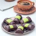 Swedish sweets punch rolls or punschrullar, covered with green marzipan, on a metal plate, served with coffee, square