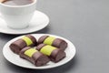 Swedish sweets punch rolls or punschrullar, covered with green marzipan, on a white plate, served with coffee, horizontal, copy