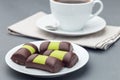 Swedish sweets punsch rolls or punschrullar, covered with green marzipan, on white plate, served with coffee, horizontal