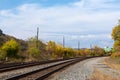 Sweeping view of railroad tracks running into the distance with seasonal fall colors, blue sky and clouds Royalty Free Stock Photo