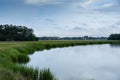 Sweeping waterway through a grassy salt marsh, treeline and early morning clouds and reflection, Mount Pleasant South Carolina