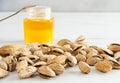 Sweet almonds in shells scattered on a white table. A glass jar with honey and a spoon is in the background. Royalty Free Stock Photo