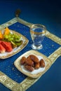 Sweet Arabian dates and fresh fruit slices with glass of water.