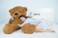 Asian girl sleeping on the bed with a big brown teddy bear. Royalty Free Stock Photo