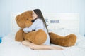 Asian girl sleeping on the bed with a big brown teddy bear. Royalty Free Stock Photo