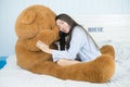 Asian girl sleeping on the bed with a big brown teddy bear. Royalty Free Stock Photo