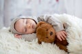 Sweet baby boy in bear overall, sleeping in bed with teddy bear Royalty Free Stock Photo