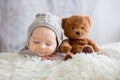 Sweet baby boy in bear overall, sleeping in bed with teddy bear Royalty Free Stock Photo