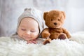 Sweet baby boy in bear overall, sleeping in bed with teddy bear Royalty Free Stock Photo