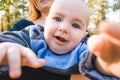 Indignant baby boy with blue eyes reaches for camera at outdoor