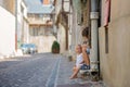Sweet baby boy, sitting on the front porch of a house in an old part of the town, smiling happily Royalty Free Stock Photo