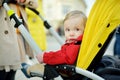 Sweet baby boy wearing red jacket sitting in a stroller outdoors. Little child in pram. Infant kid in pushchair. Spring walks with Royalty Free Stock Photo