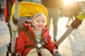 Sweet baby boy wearing red jacket sitting in a stroller outdoors. Little child in pram. Infant kid in pushchair. Spring walks with Royalty Free Stock Photo