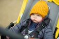 Sweet baby boy wearing warm clothes sitting in a stroller outdoors. Little child in pram. Infant kid in pushchair. Autumn walks Royalty Free Stock Photo