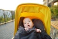 Sweet baby boy wearing warm clothes sitting in a stroller outdoors. Little child in pram. Infant kid in pushchair. Autumn walks Royalty Free Stock Photo