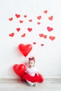 Sweet baby girl with red heart. Happy little girl with red balloon at a blank brick wall.