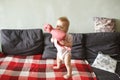 Sweet baby girl standing on her little feet on a couch at home, playing Royalty Free Stock Photo