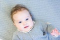 Sweet baby girl in a warm knitted sweater on a cable knit blanket Royalty Free Stock Photo