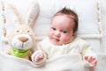 Sweet baby girl in a white crib with bunny toy Royalty Free Stock Photo